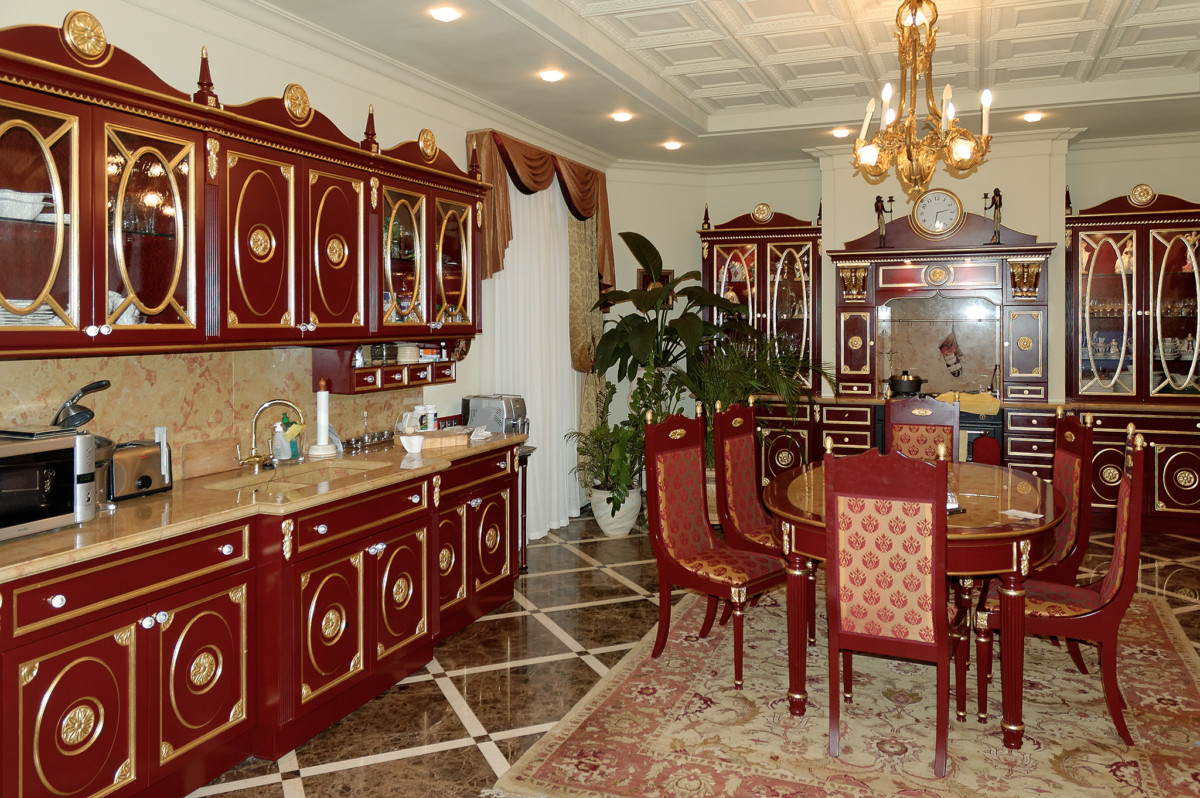 Кухня обеденный стол со стульями выполнены нарочито ярко, с покрытием в насыщенном вишнёвом лаке и отделке золотым декором.